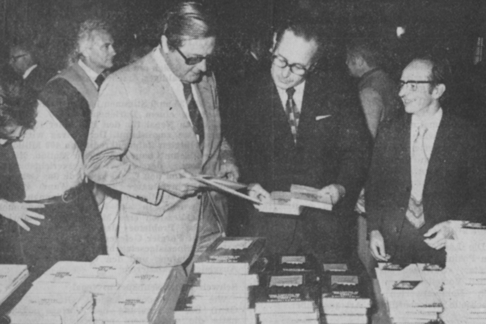 Zwei Männer im Anzug blättern in Büchern.