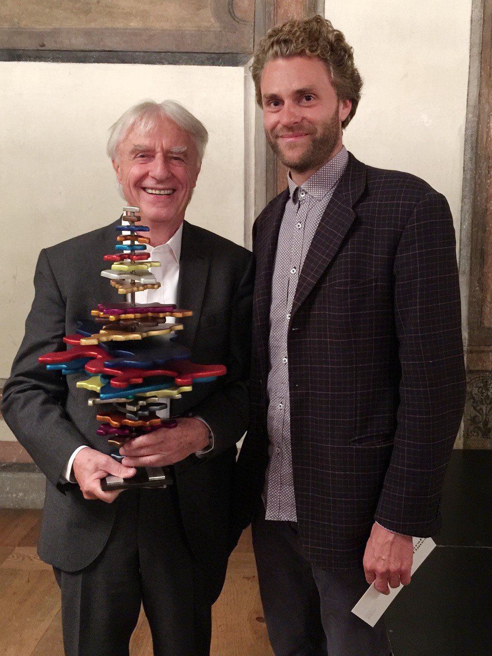 Beide Männer halten die Trophäe und lächeln